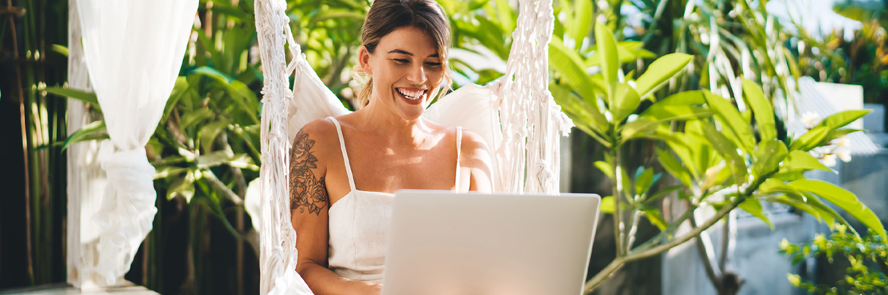 female student in a hammock working on her laptop